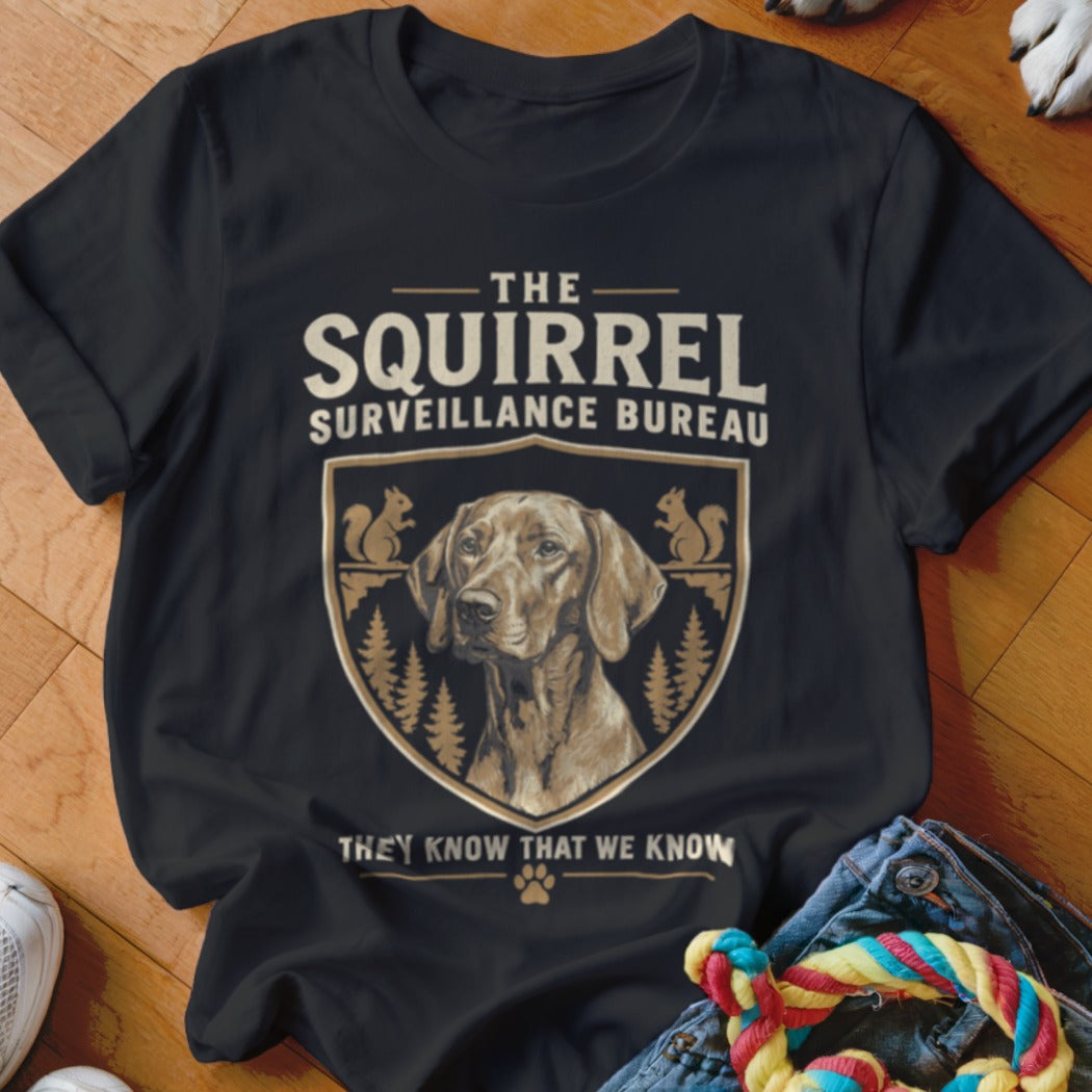 Black t-shirt featuring a crest with a dog portrait, squirrels, and the text The Squirrel Surveillance Bureau.