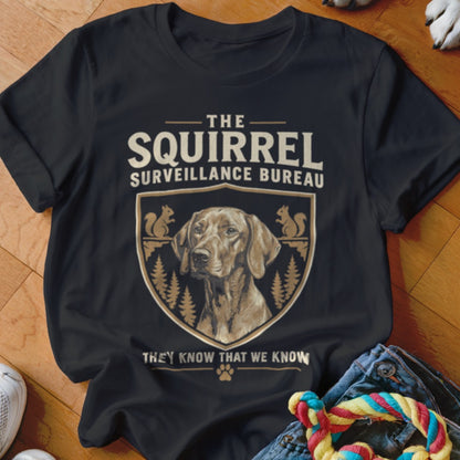 Black t-shirt featuring a crest with a dog portrait, squirrels, and the text The Squirrel Surveillance Bureau.