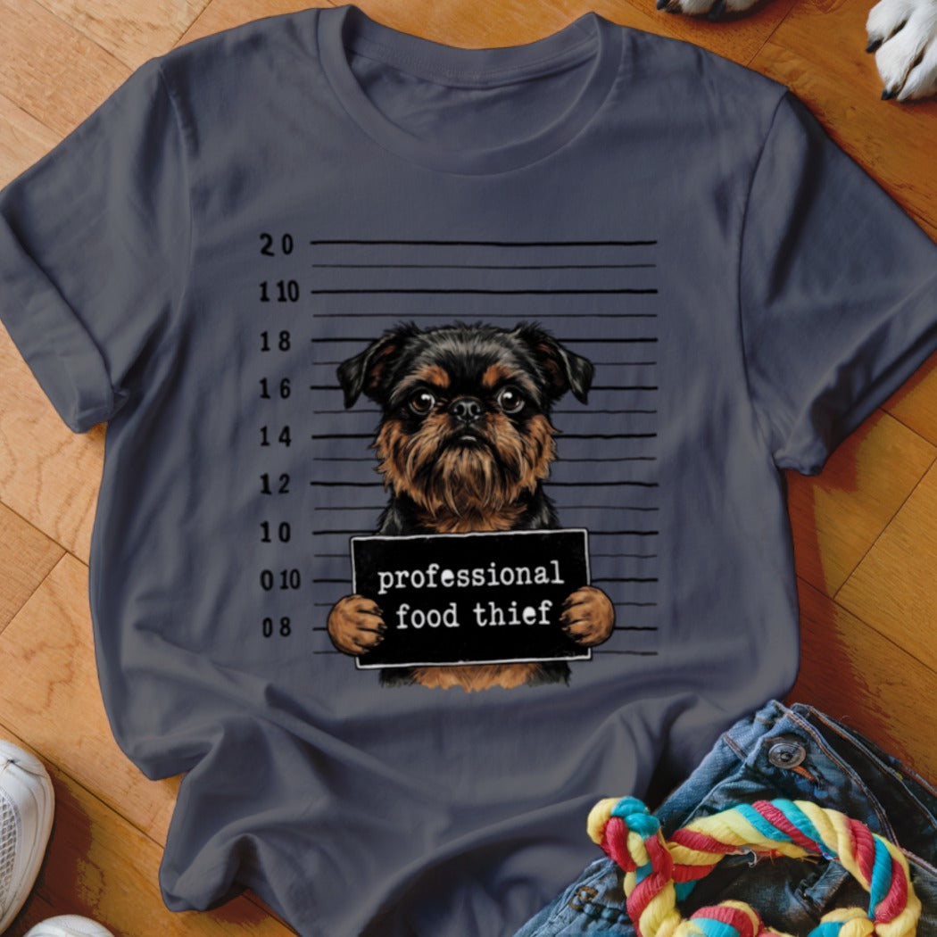 Griffon dog mugshot with "professional food thief" sign on a dark t-shirt.