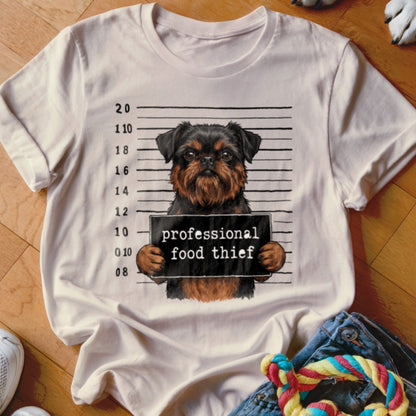 Grizzled dog with a mugshot sign reading "professional food thief" on a t-shirt.