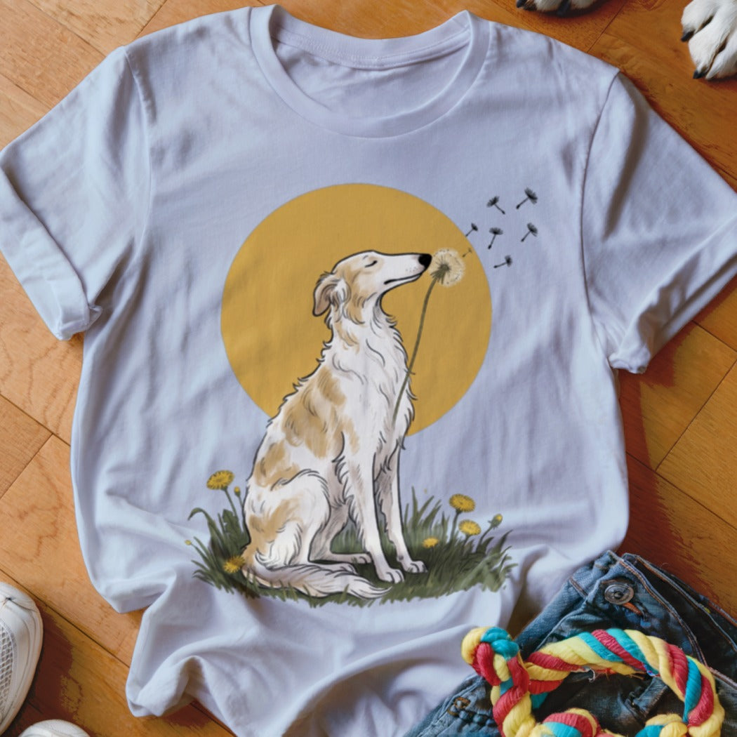 White t-shirt featuring an illustration of a dog sitting in grass and blowing dandelion seeds.