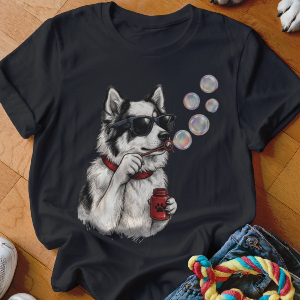 A black t-shirt printed with a graphic of a husky wearing sunglasses and blowing soap bubbles.