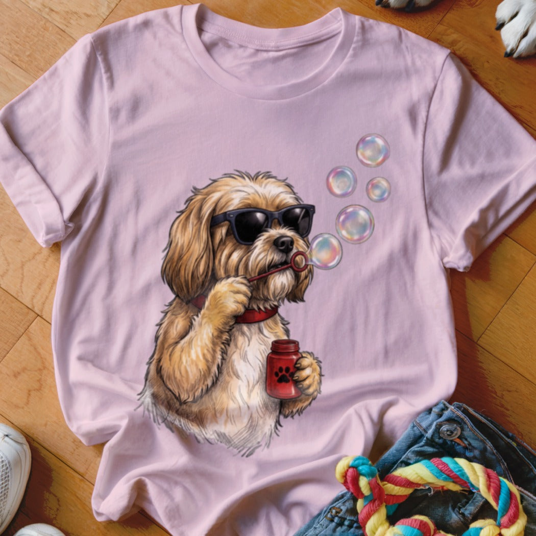 Light pink t-shirt featuring an illustration of a fluffy brown dog wearing sunglasses and blowing bubbles.