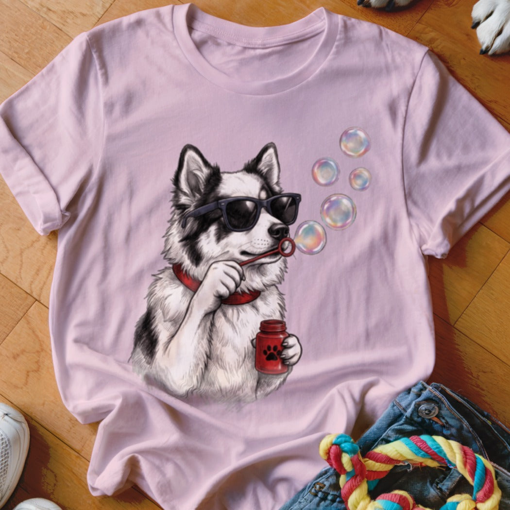 A light pink t-shirt featuring an illustration of a dog wearing sunglasses and blowing bubbles.