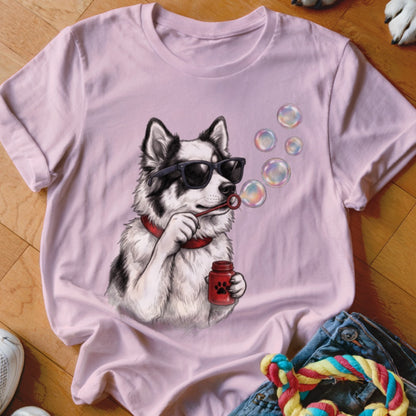 A light pink t-shirt featuring an illustration of a dog wearing sunglasses and blowing bubbles.