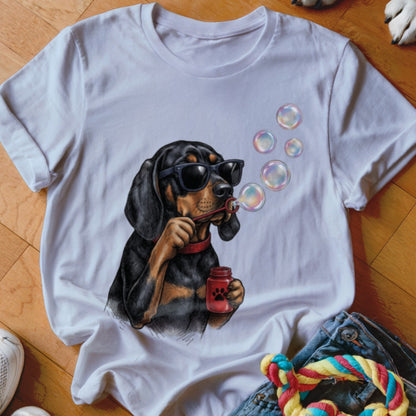 A white t-shirt featuring a graphic of a black and tan dog wearing sunglasses and blowing bubbles.