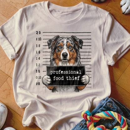 T-shirt graphic of a dog in a mugshot holding a sign reading "professional food thief."