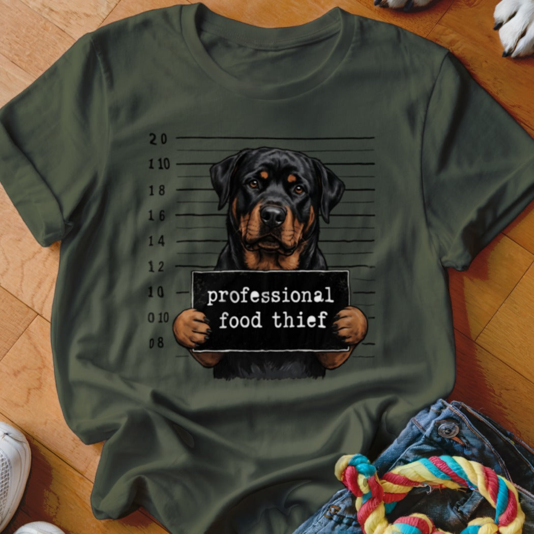 Rottweiler mugshot with sign reading "professional food thief" on a green t-shirt.