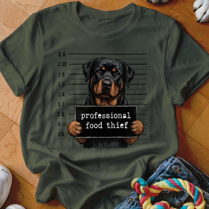 Rottweiler mugshot with sign reading "professional food thief" on a green t-shirt.