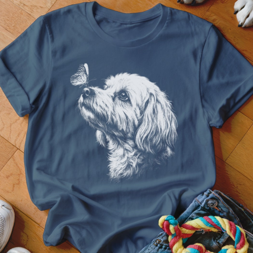 A dark blue crewneck t-shirt featuring a white sketch of a fluffy dog looking at a butterfly on its nose.