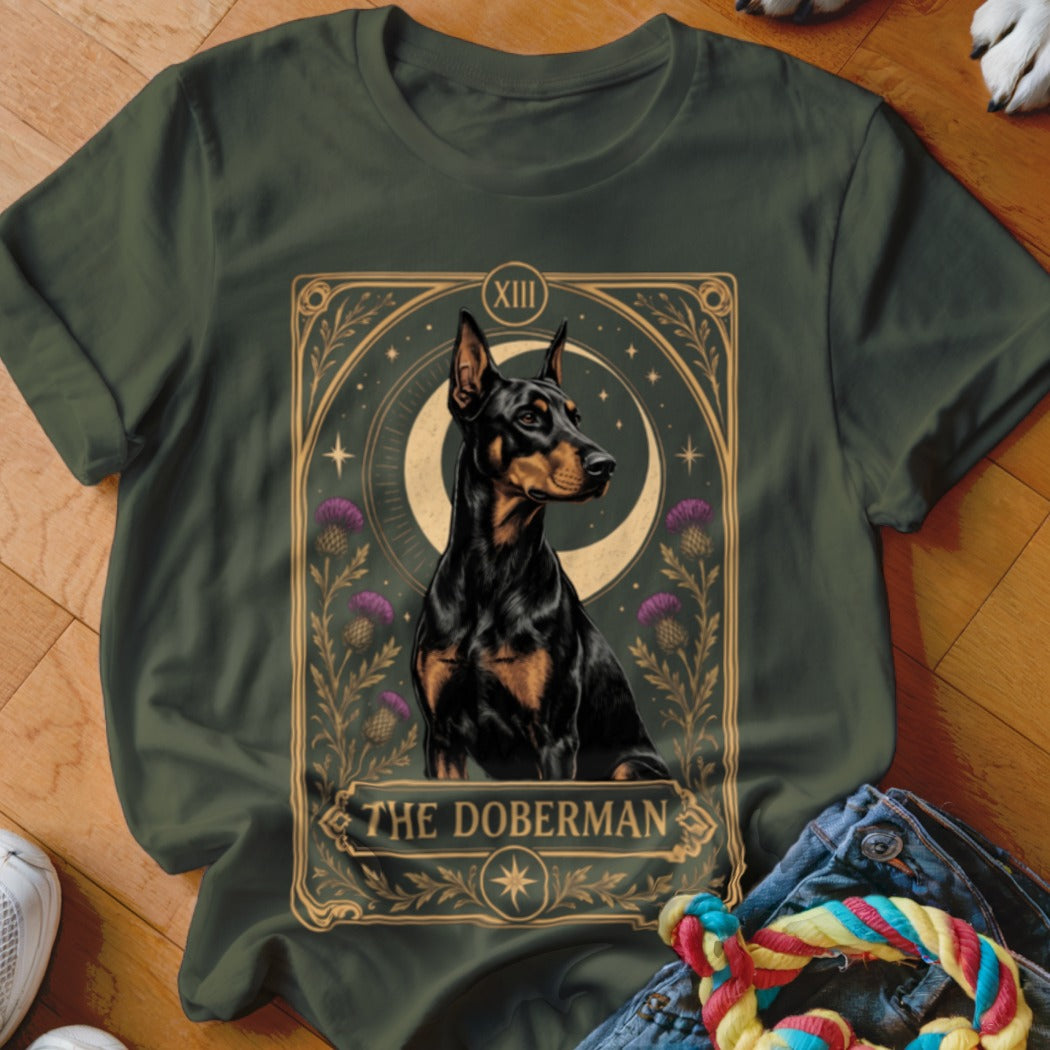 Dark green t-shirt featuring a tarot card graphic of a Doberman surrounded by thistles and a crescent moon.