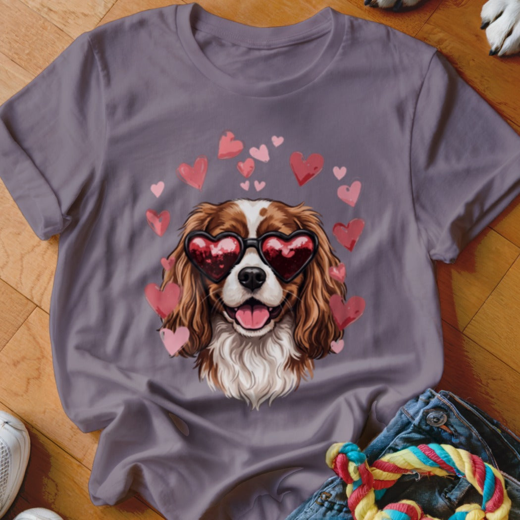 A grey crewneck t-shirt featuring a graphic of a brown and white spaniel wearing heart-shaped sunglasses surrounded by pink hearts.