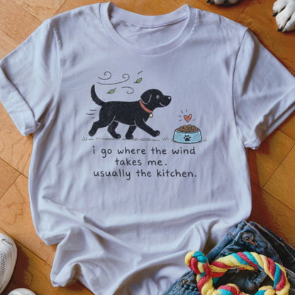 White t-shirt with black dog graphic and text "I go where the wind takes me. Usually the kitchen."