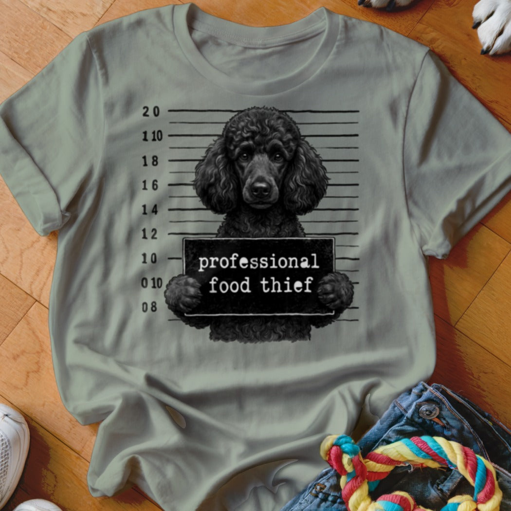 Black poodle mugshot with "professional food thief" sign.