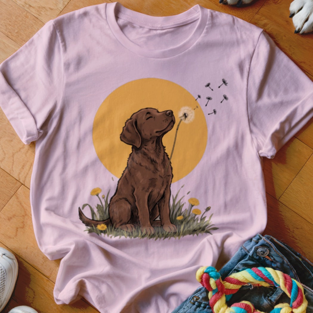 A light pink crewneck t-shirt featuring a graphic of a brown dog blowing a dandelion.