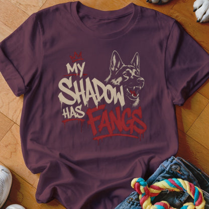 Maroon t-shirt with a graphic of a German Shepherd and the text "MY SHADOW HAS FANGS".