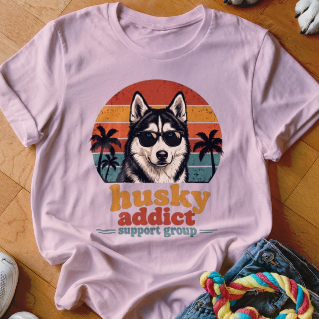 Light pink t-shirt featuring a retro graphic of a husky wearing sunglasses with sunset and palm trees.