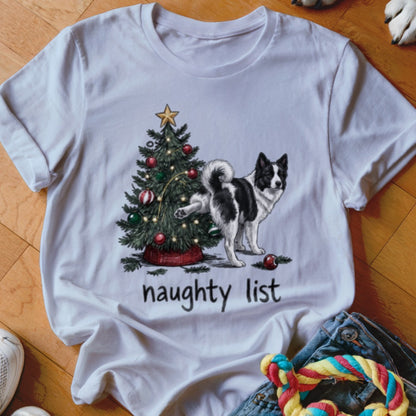 A white t-shirt featuring an illustration of a black and white dog peeing on a Christmas tree, with the text naughty list underneath.