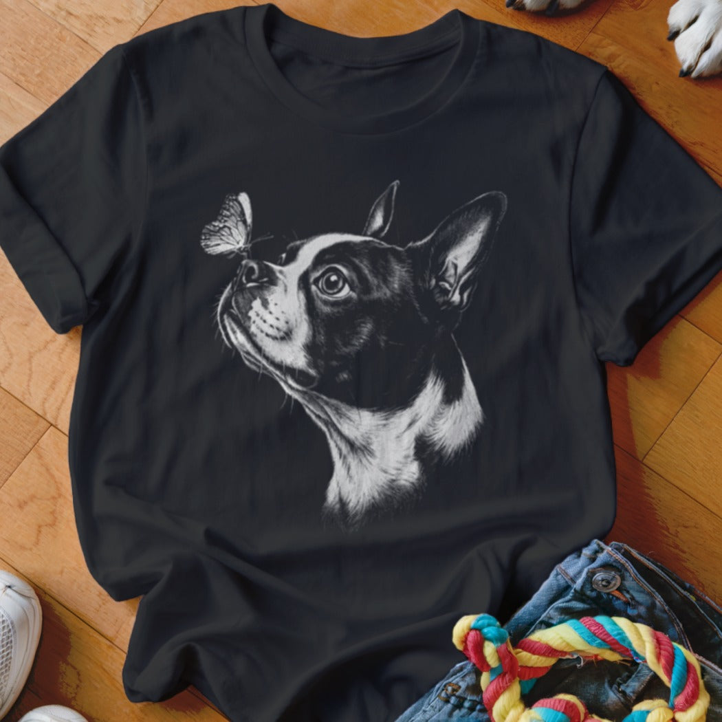 A black t-shirt printed with a detailed sketch of a Boston Terrier looking at a butterfly on its nose.