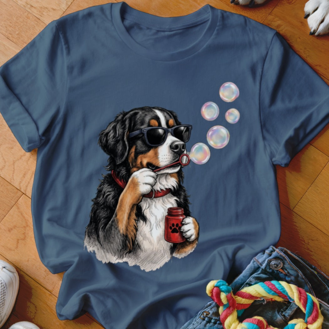 Blue t-shirt featuring a graphic of a Bernese Mountain Dog wearing sunglasses and blowing soap bubbles.