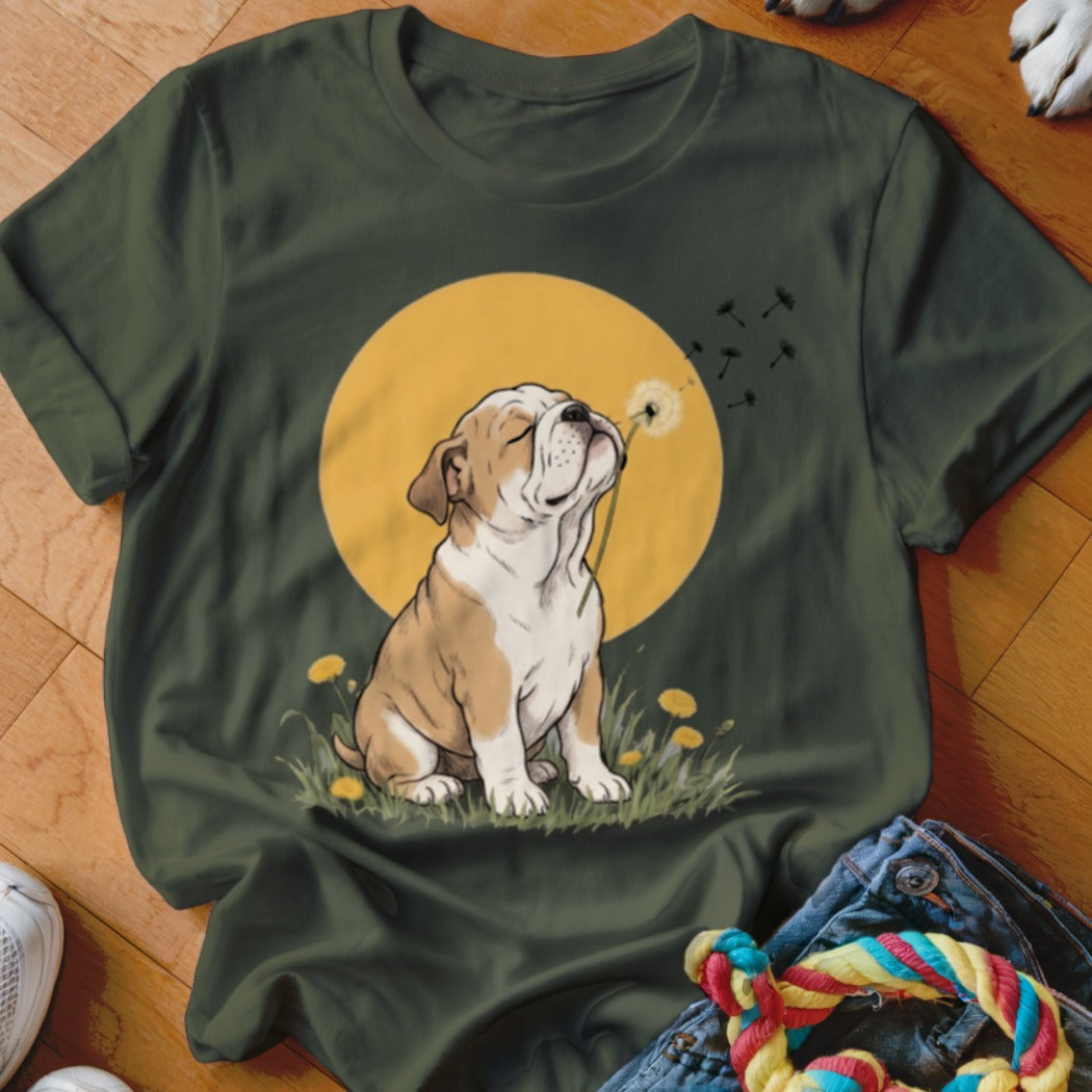 Dark green t-shirt featuring a graphic of an English bulldog puppy blowing dandelion seeds against a yellow sun.