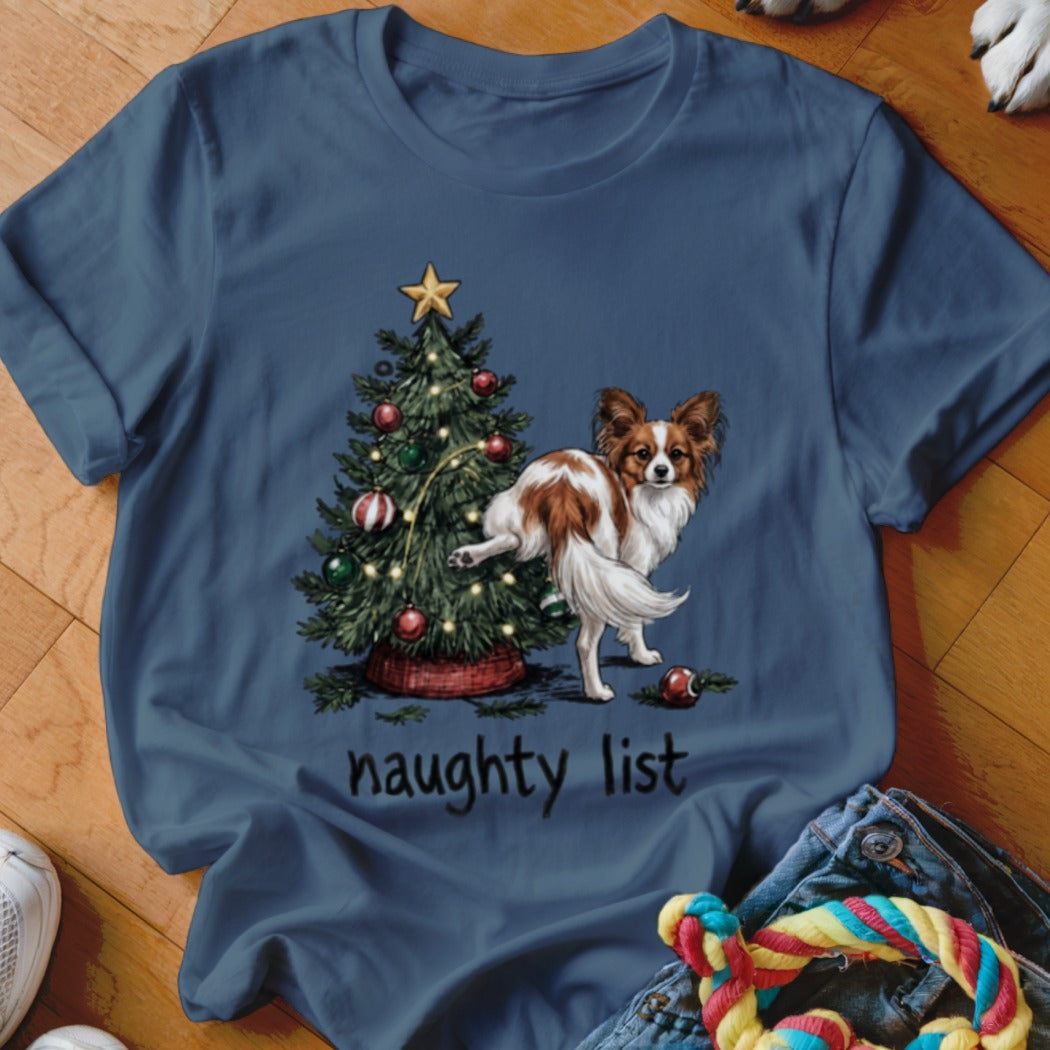 Papillon dog by Christmas tree with "naughty list" text.