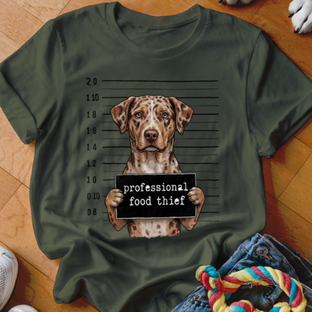 Leopard print dog holding "professional food thief" sign against mugshot background.