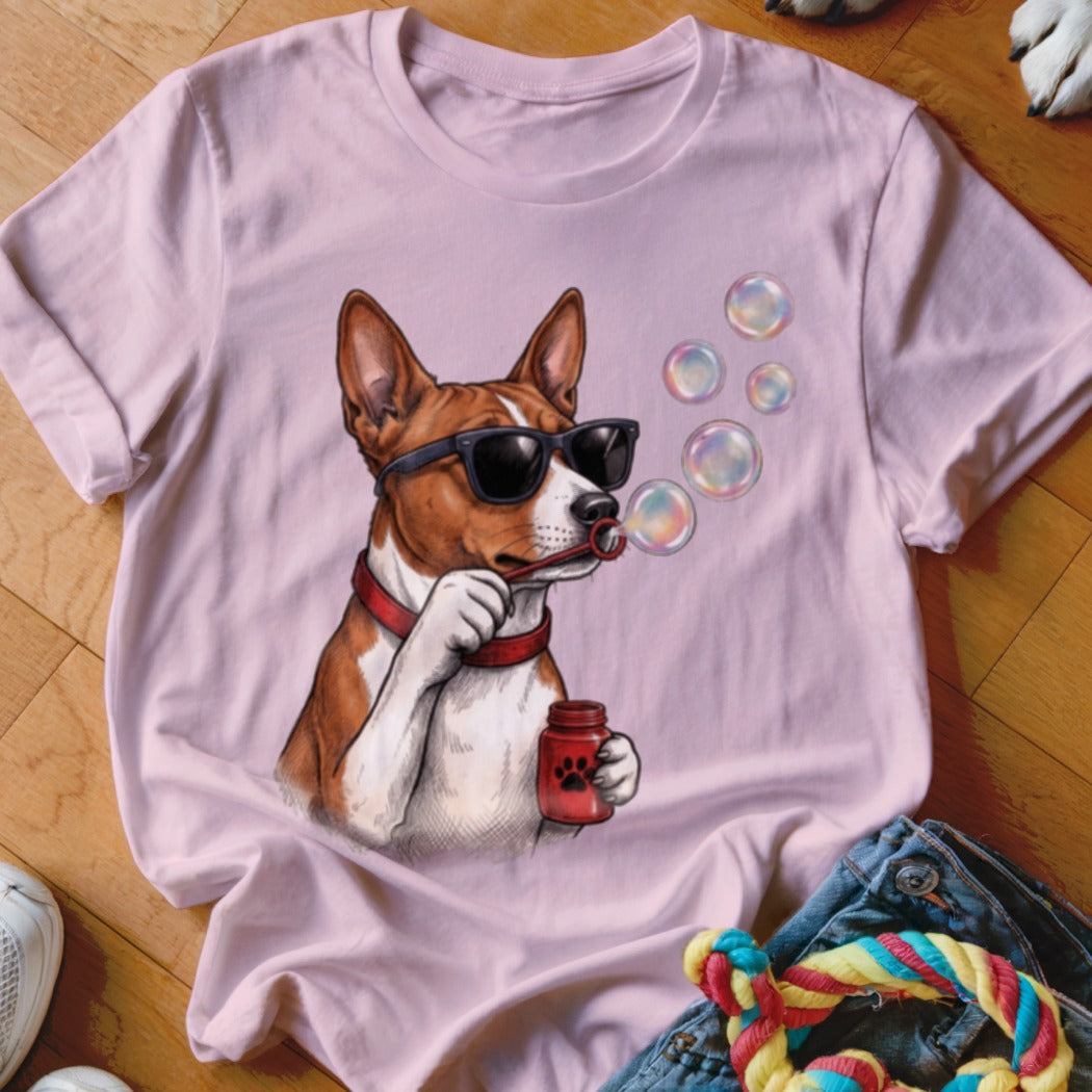 A light pink t-shirt printed with a graphic of a dog wearing sunglasses and blowing soap bubbles.