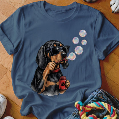 Blue t-shirt featuring an illustration of a black and tan dog wearing sunglasses and blowing soap bubbles.