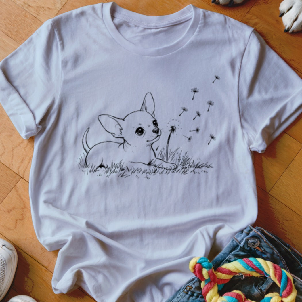 A white crewneck t-shirt featuring a black line art graphic of a puppy blowing dandelion seeds.