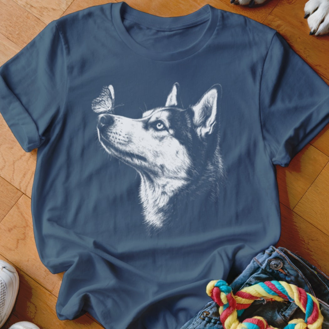 A dark blue t-shirt featuring a white sketch graphic of a husky looking at a butterfly on its nose.