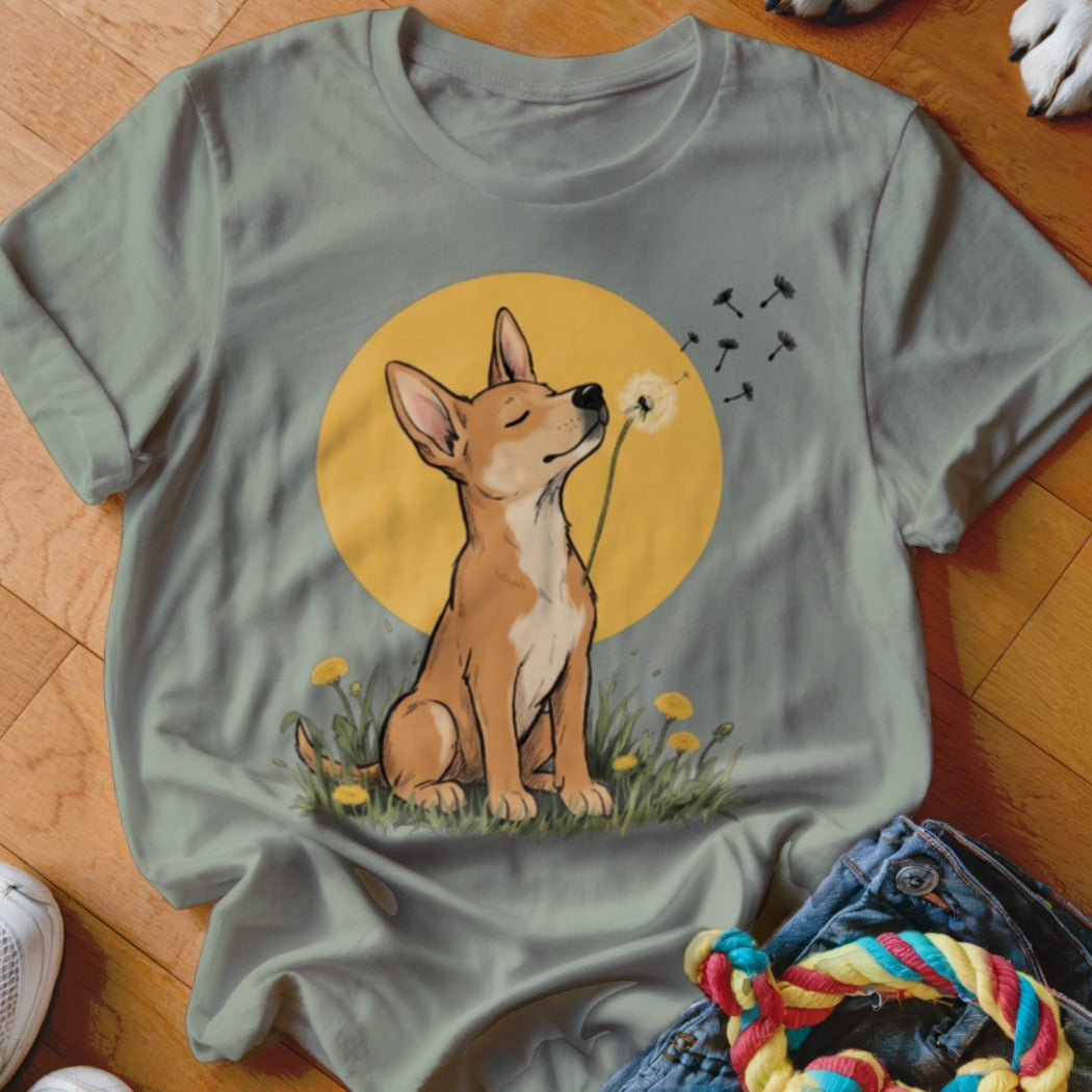 Sage green crewneck t-shirt featuring an illustration of a brown dog blowing dandelion seeds against a yellow circle.