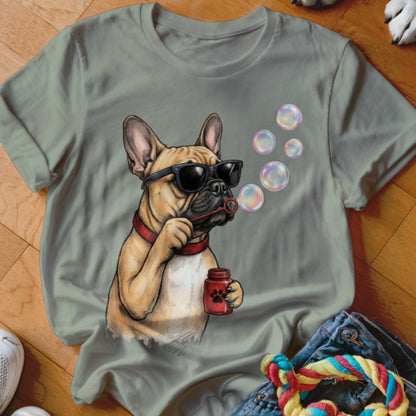 Sage green t-shirt featuring an illustration of a French bulldog wearing sunglasses and blowing soap bubbles.