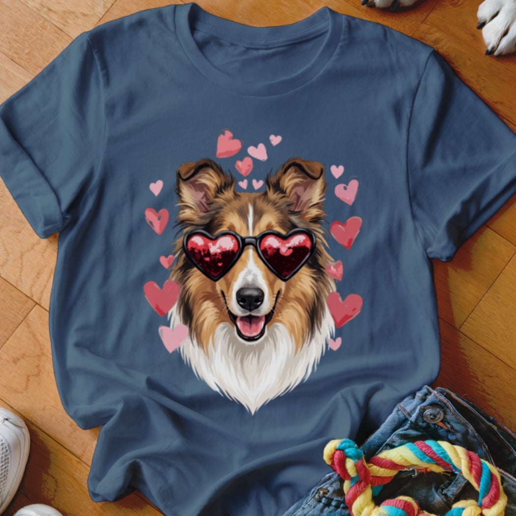 A dark blue t-shirt printed with an illustration of a Sheltie dog wearing heart-shaped sunglasses surrounded by pink hearts.