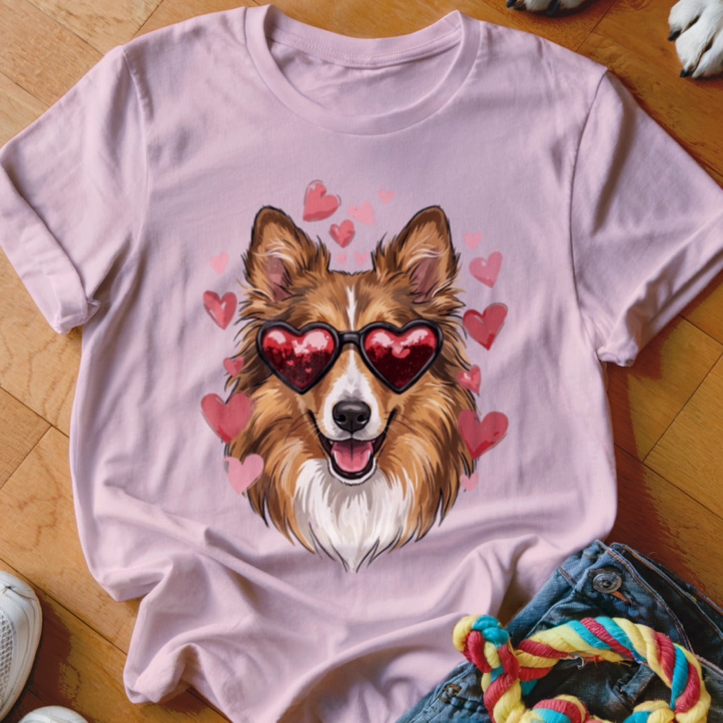 Pink t-shirt featuring an illustration of a brown and white dog wearing heart-shaped sunglasses surrounded by floating pink hearts.
