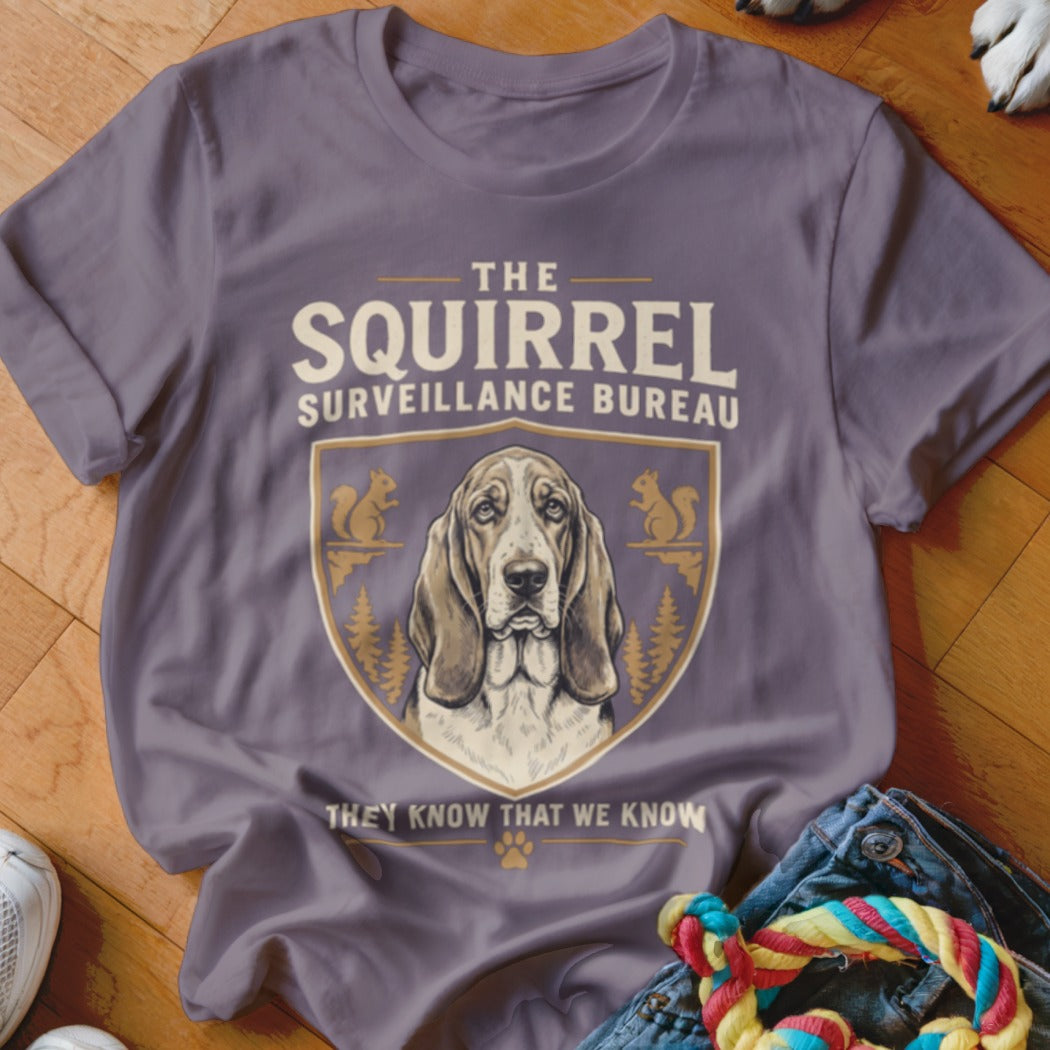 A grey t-shirt featuring a basset hound graphic with the text The Squirrel Surveillance Bureau.