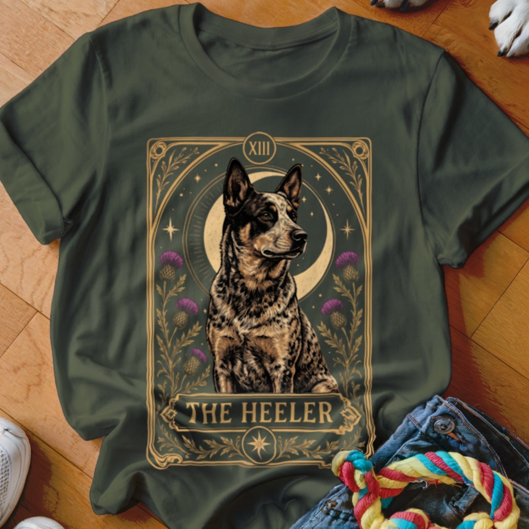 Dark green t-shirt featuring a tarot card style graphic of an Australian Cattle Dog with purple flowers and the text The Heeler.