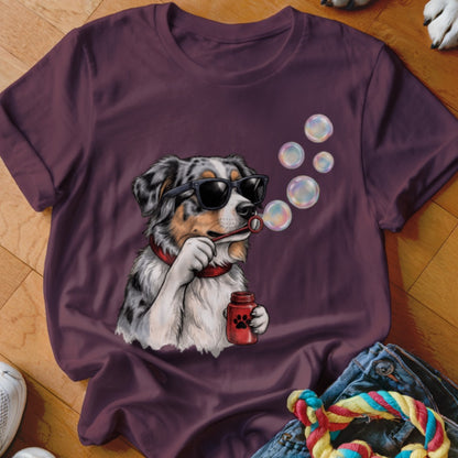 Plum-colored t-shirt featuring a graphic of an Australian Shepherd wearing sunglasses and blowing bubbles.