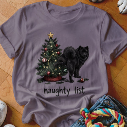 Black dog by a Christmas tree with text "naughty list" on shirt.