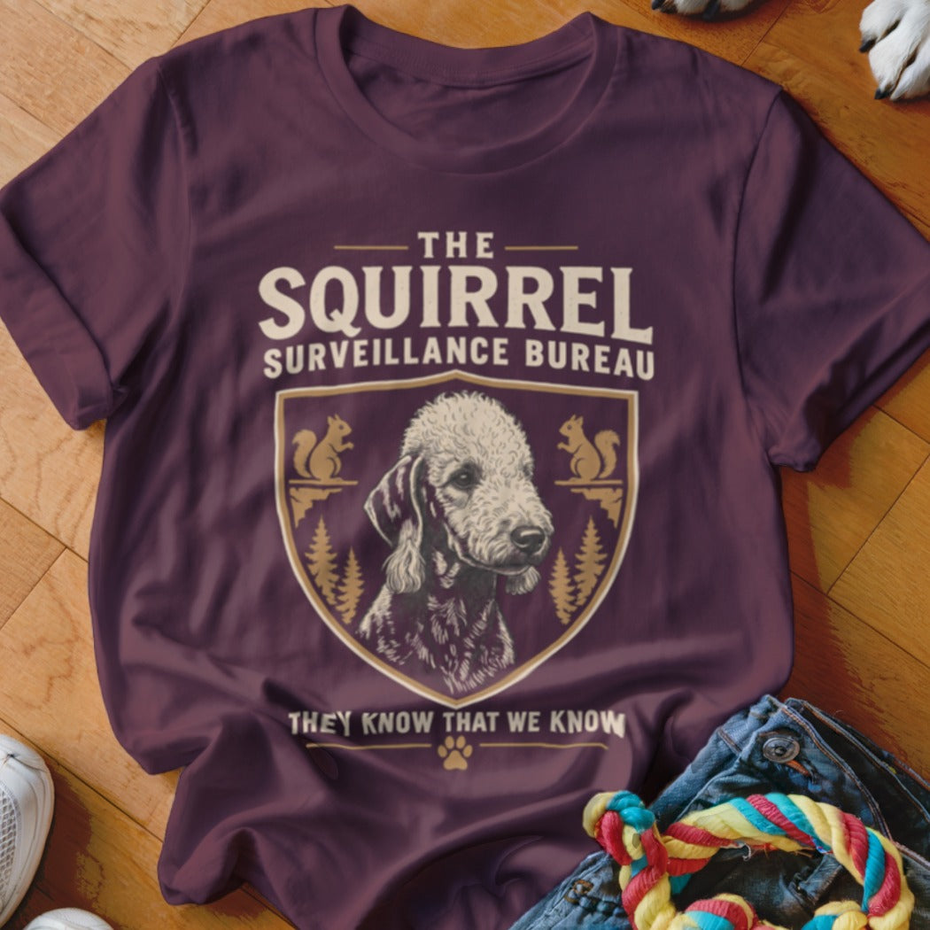 Maroon t-shirt featuring a dog graphic, crest, and text reading The Squirrel Surveillance Bureau.