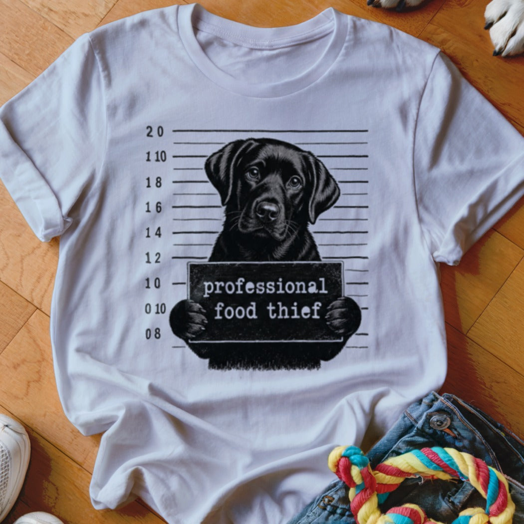 White t-shirt graphic of a black lab holding a "professional food thief" sign.