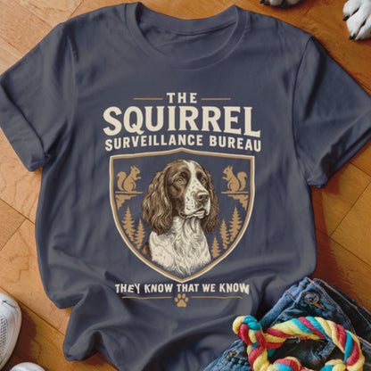 Dark gray t-shirt featuring a crest with a spaniel, squirrels, and the text The Squirrel Surveillance Bureau.