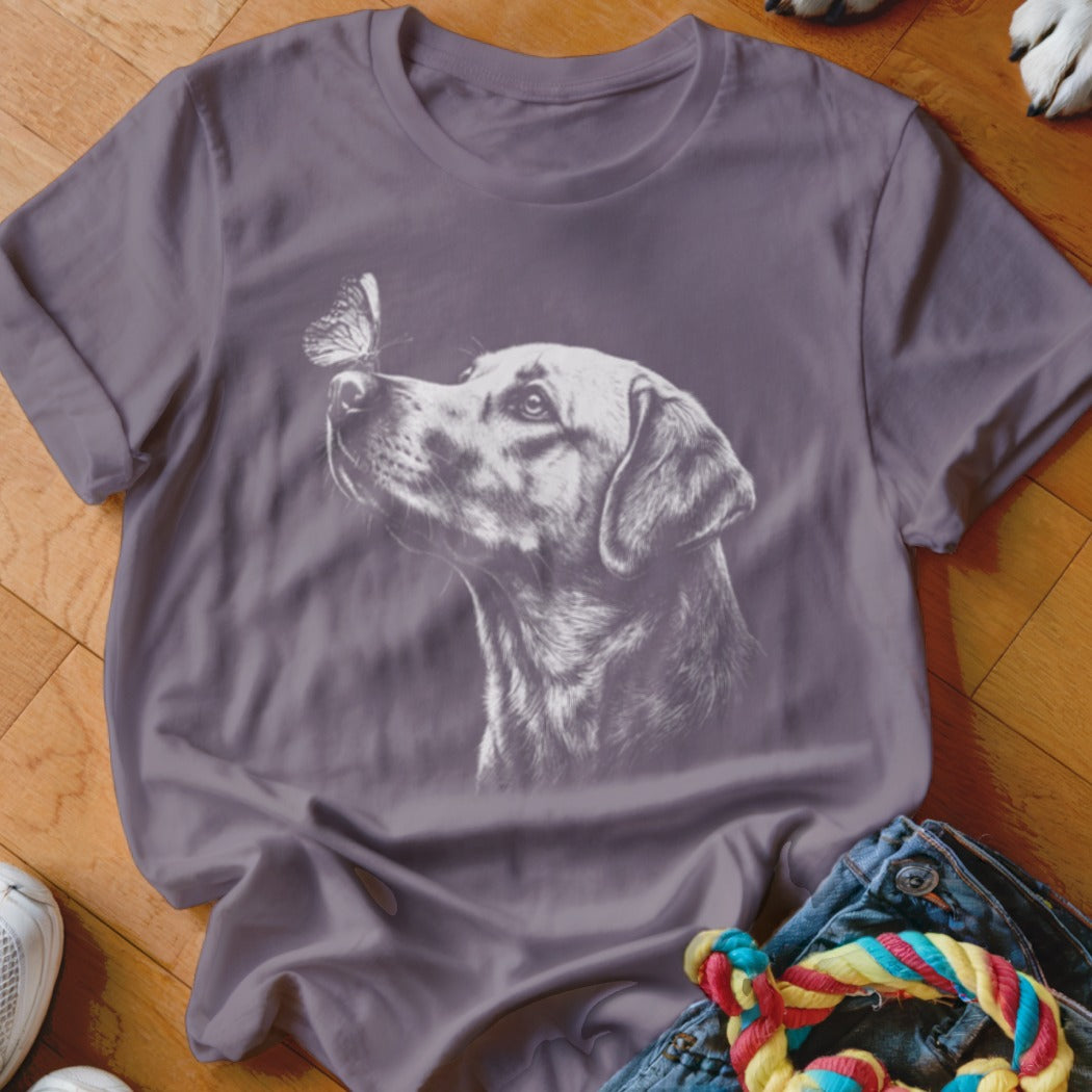 A purple short-sleeved t-shirt featuring a white sketched graphic of a dog looking at a butterfly.