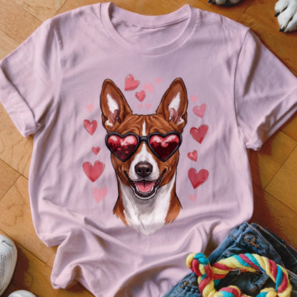 A light pink t-shirt features a graphic of a brown and white dog wearing heart-shaped sunglasses surrounded by pink hearts.