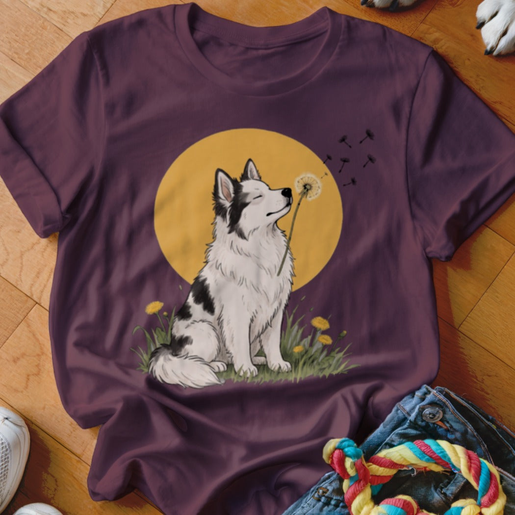 A dark purple t-shirt features a graphic of a black and white dog sniffing a dandelion against a yellow circle.