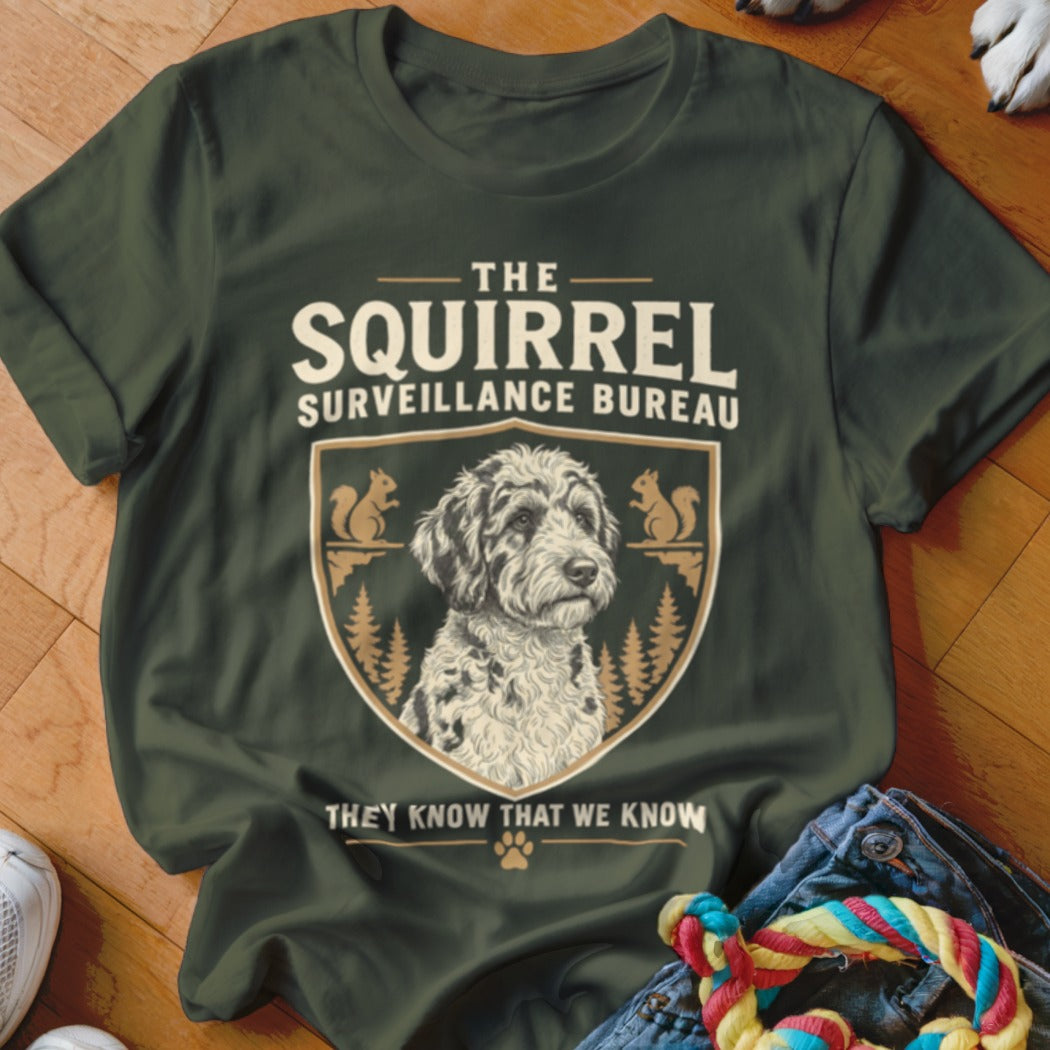 Dark green t-shirt featuring a dog graphic, crest, squirrels, and the text "The Squirrel Surveillance Bureau".