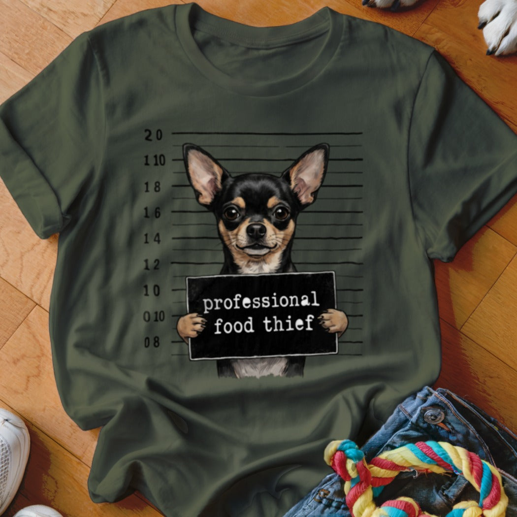 Chihuahua mugshot with "professional food thief" sign on green t-shirt.