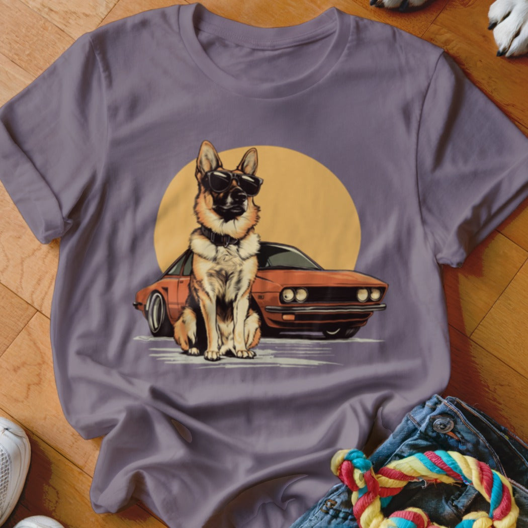 German Shepherd wearing sunglasses with a vintage car and yellow sun on a purple shirt.