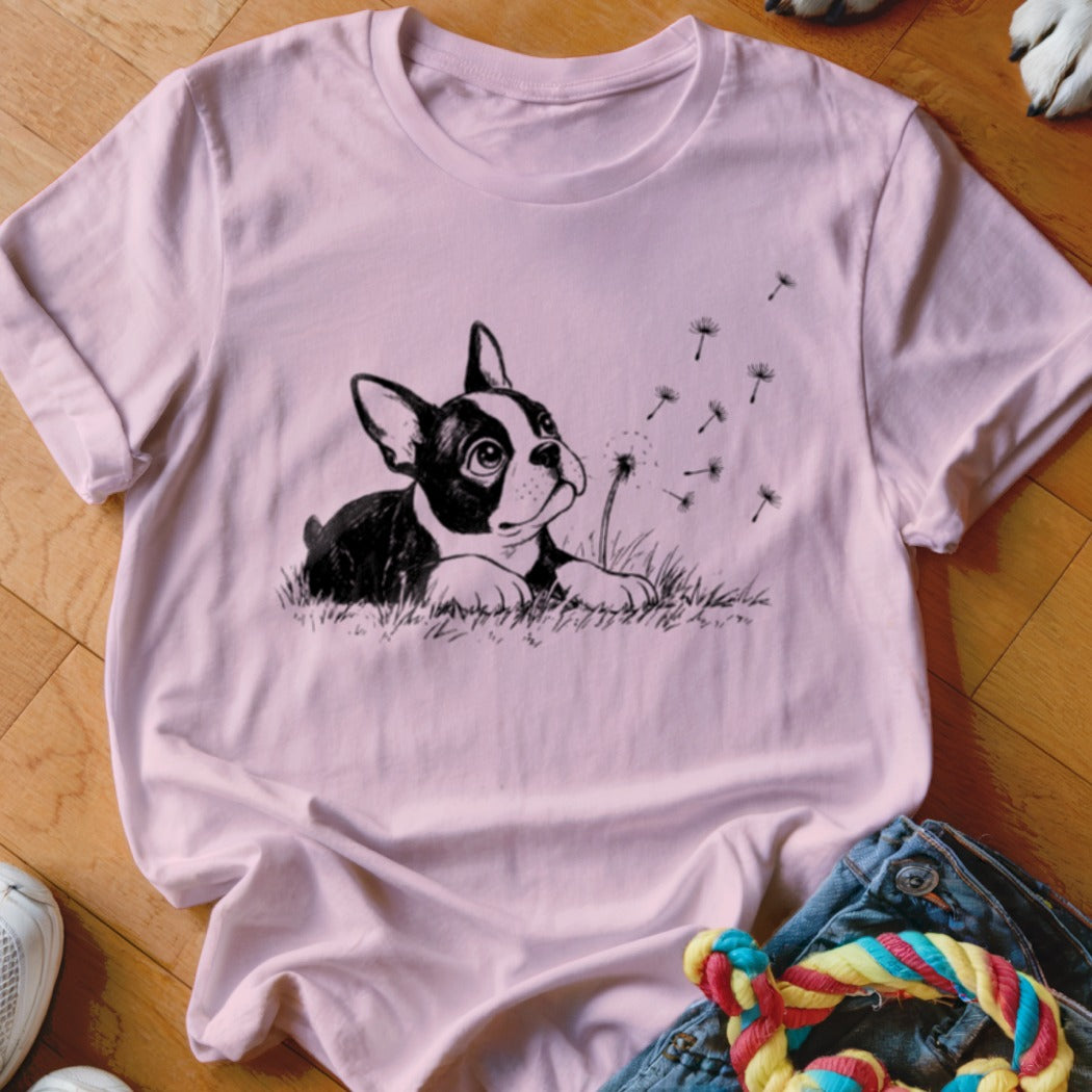 Light pink crewneck t-shirt featuring a black and white illustration of a Boston Terrier puppy blowing dandelion seeds.