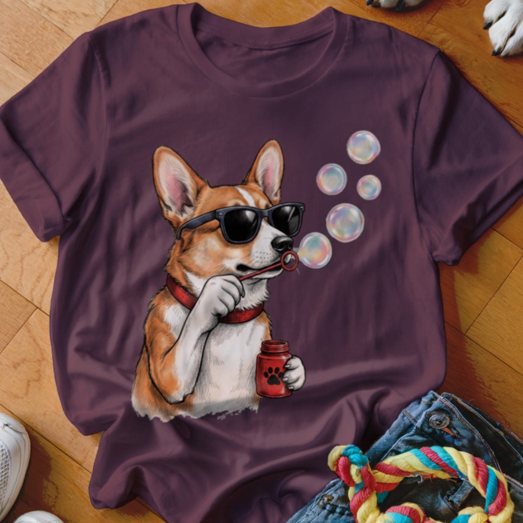 Maroon t-shirt featuring a graphic of a corgi wearing sunglasses and blowing soap bubbles.